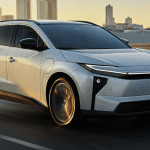 white 2026 Toyota bZ driving on road with skyline In the back